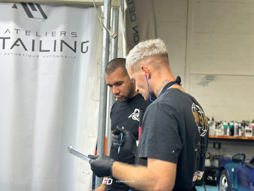 Deux hommes vérifient une tablette dans atelier auto