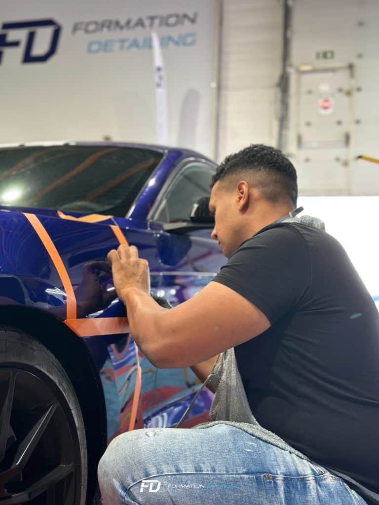 Homme appliquant vinyle sur voiture bleue
