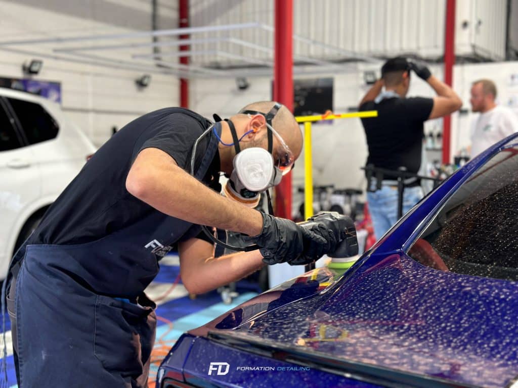 Homme polissant une voiture dans un atelier