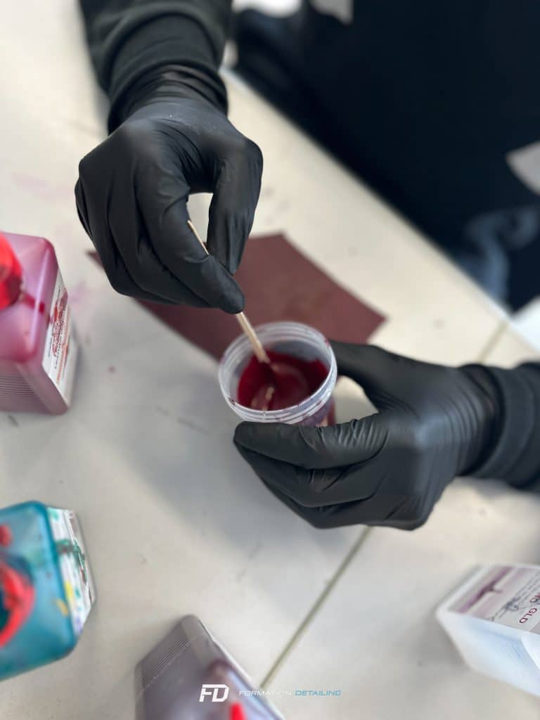 Mains gantées mélangeant peinture rouge