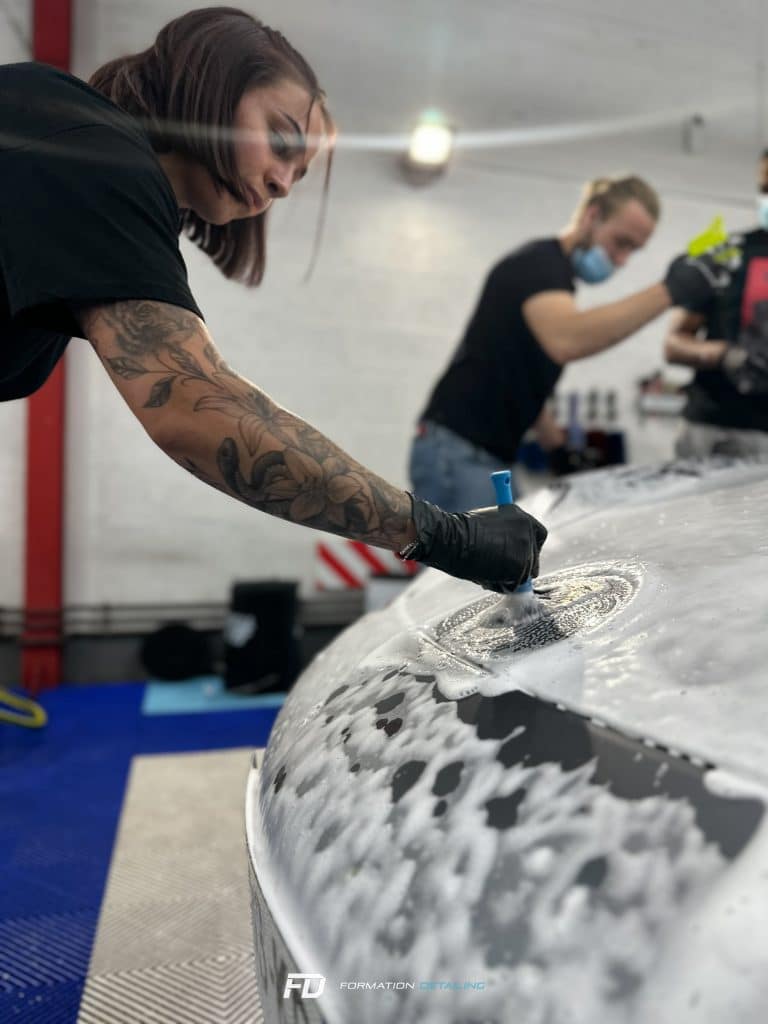 Personne tatouée lavant une voiture