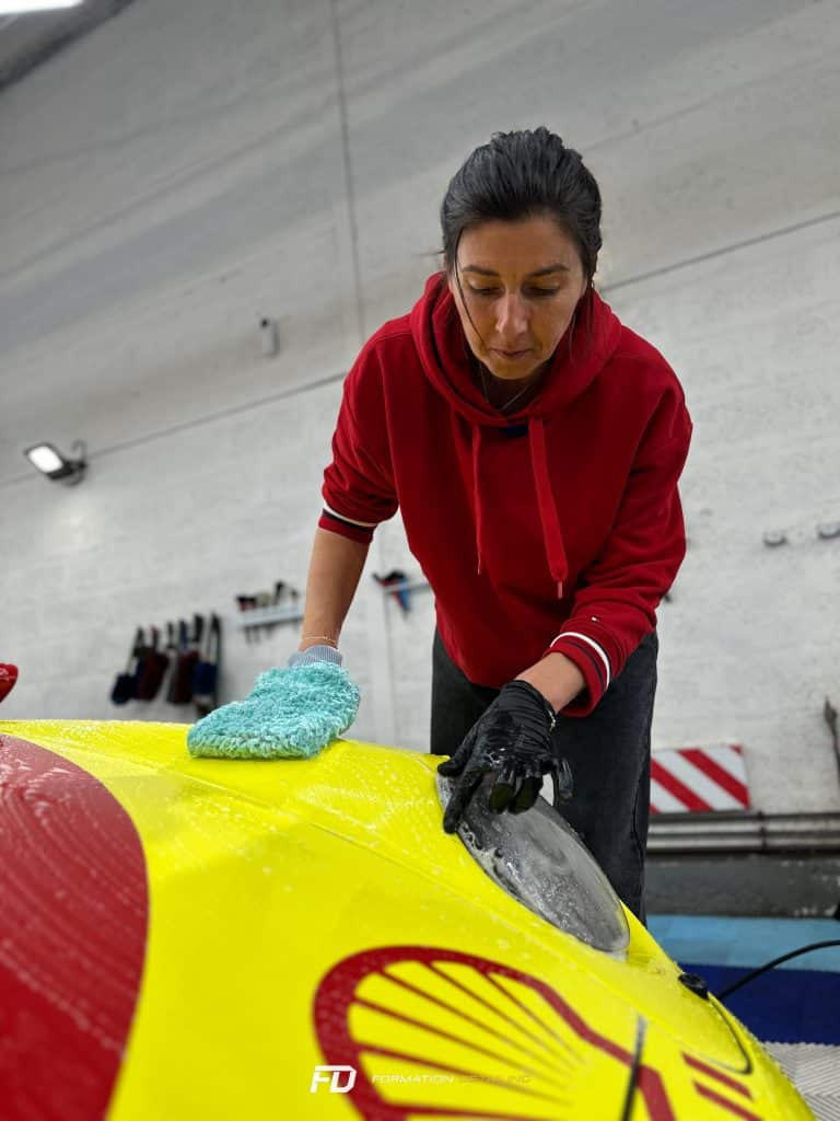 Femme nettoyant méticuleusement une voiture jaune