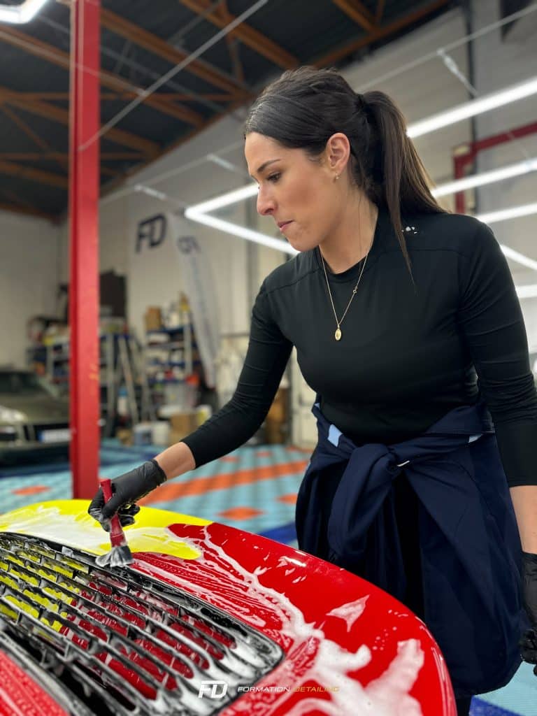 Femme nettoyant attentivement voiture rouge