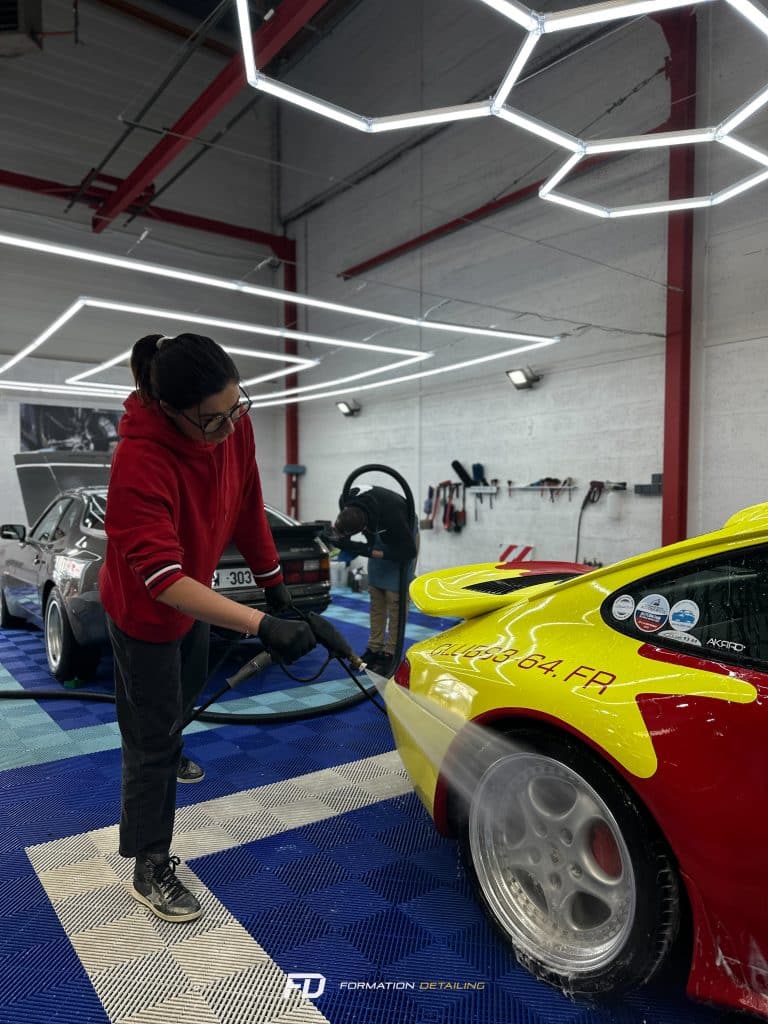 Femme nettoyant voiture de course en atelier