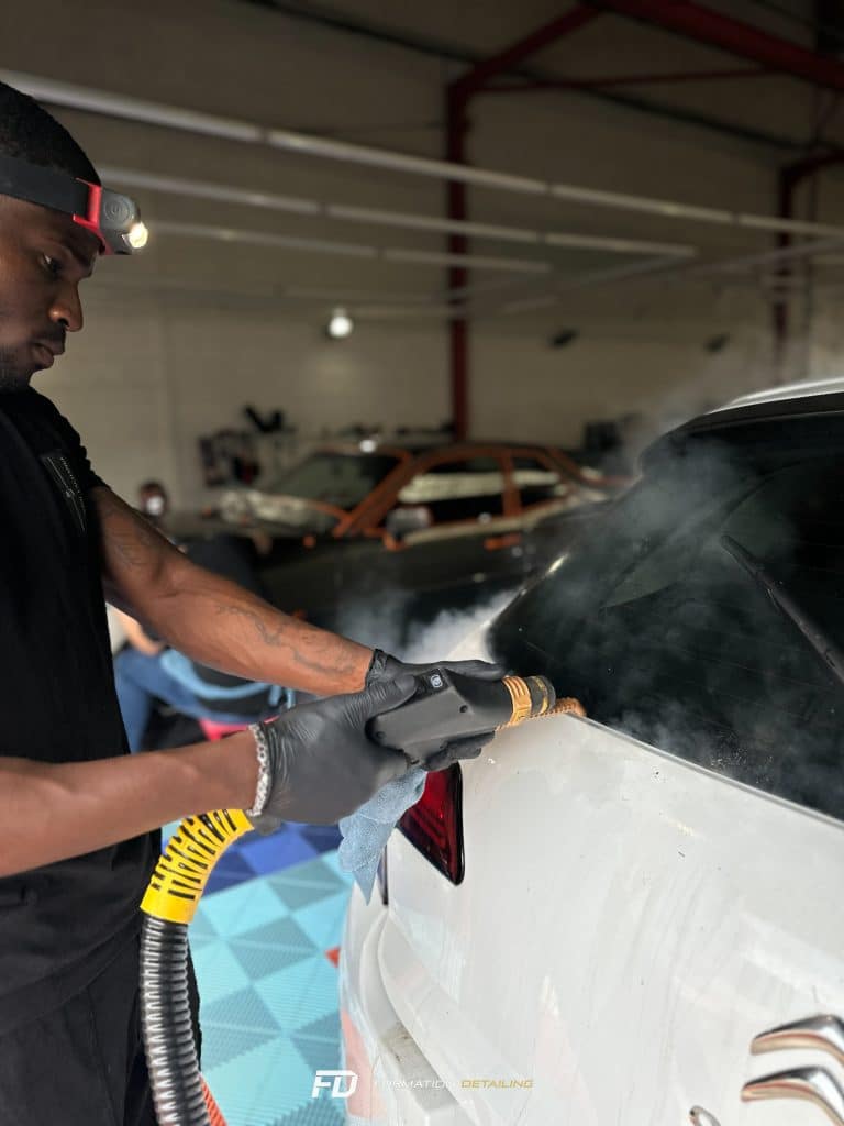 Homme nettoyant voiture avec vapeur dans garage