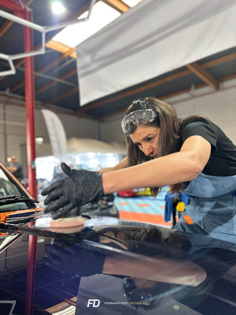 Femme polissant voiture en atelier