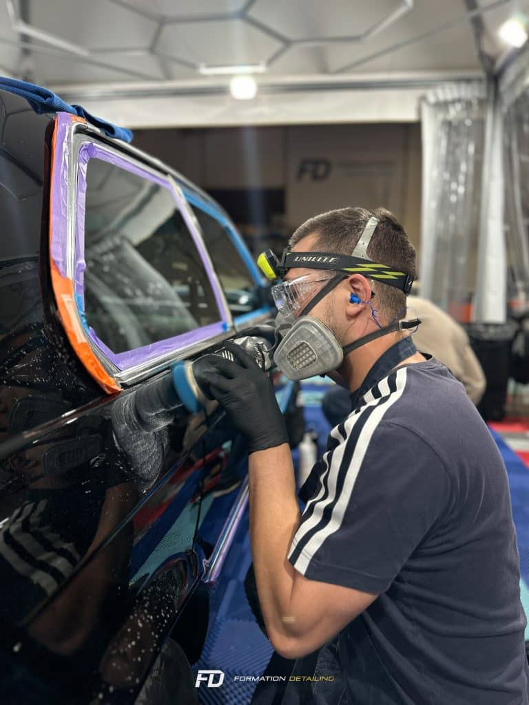 Homme polissant voiture avec équipement de protection