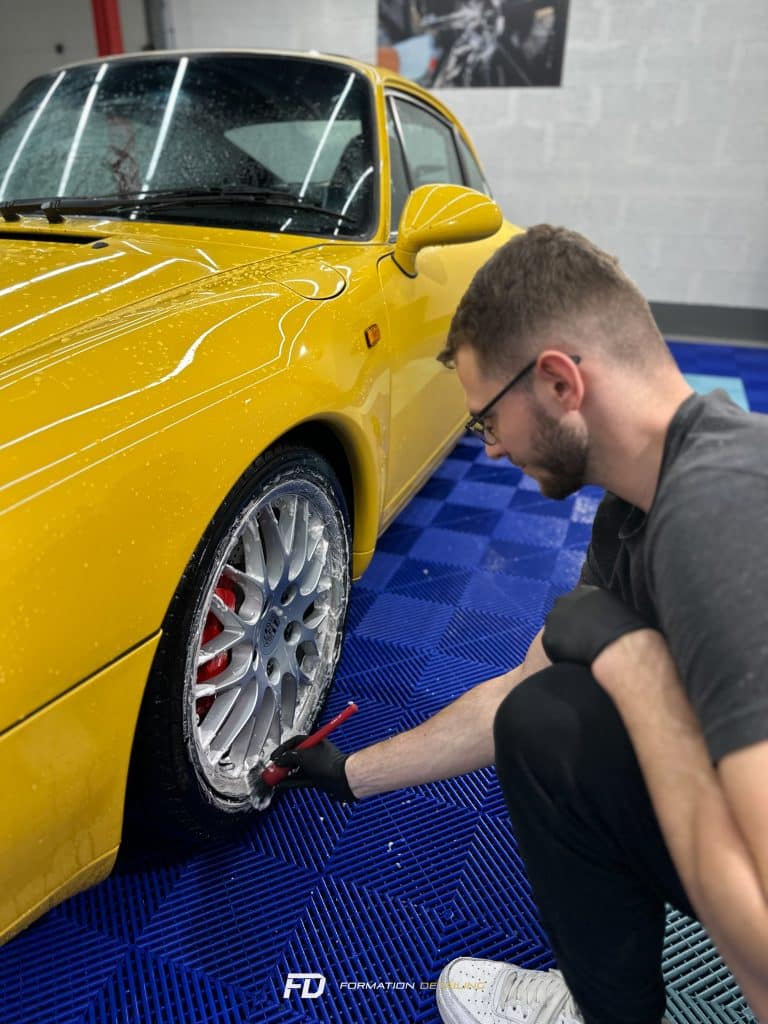 Homme inspectant pneu de voiture jaune