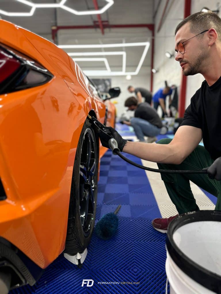 Homme nettoyant méticuleusement une voiture orange
