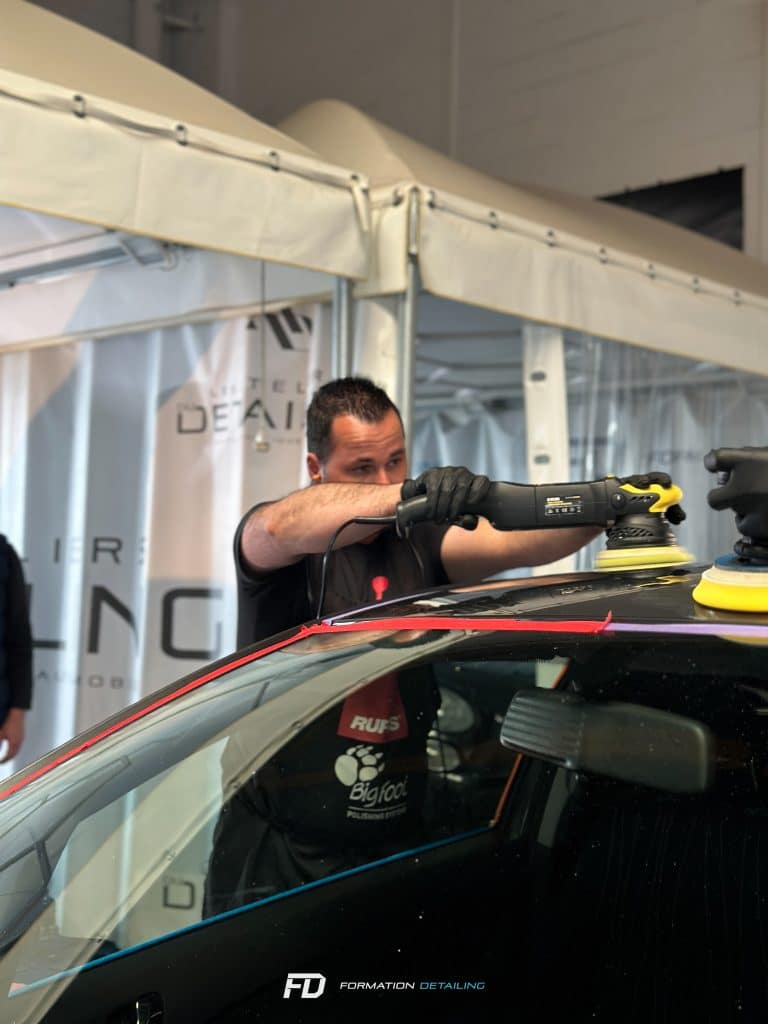 Homme utilisant une polisseuse sur une voiture noire